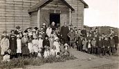 Vice Provincial Patrick Mulhall and Fr. Augustine Duke with congregation outside of the church. East Kildonan, Winnipeg, MB, 1914.